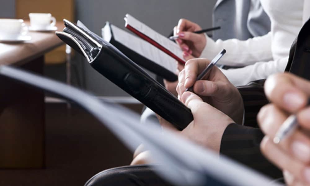 people sitting down taking notes on notebooks