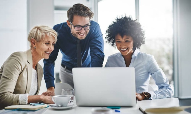 three people looking at a laptop