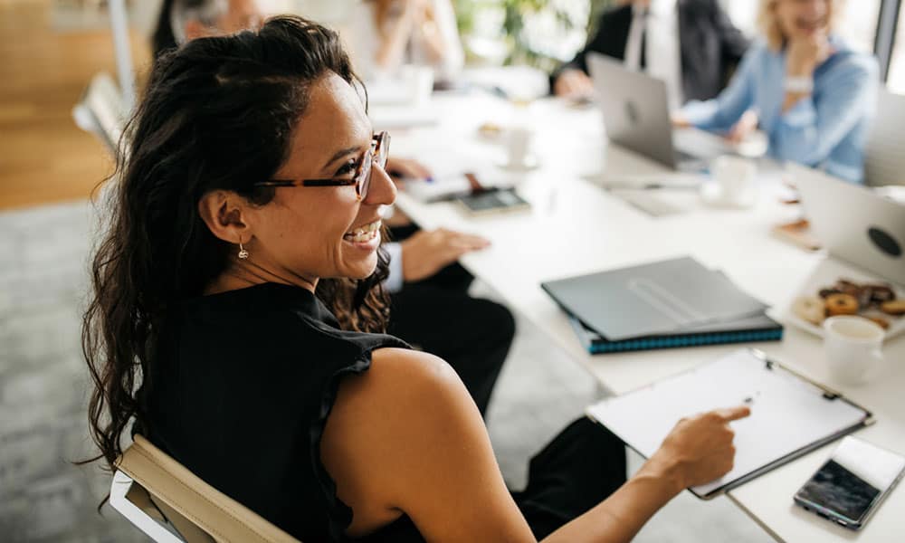 women with glasses sitting in office during a meeting smiling