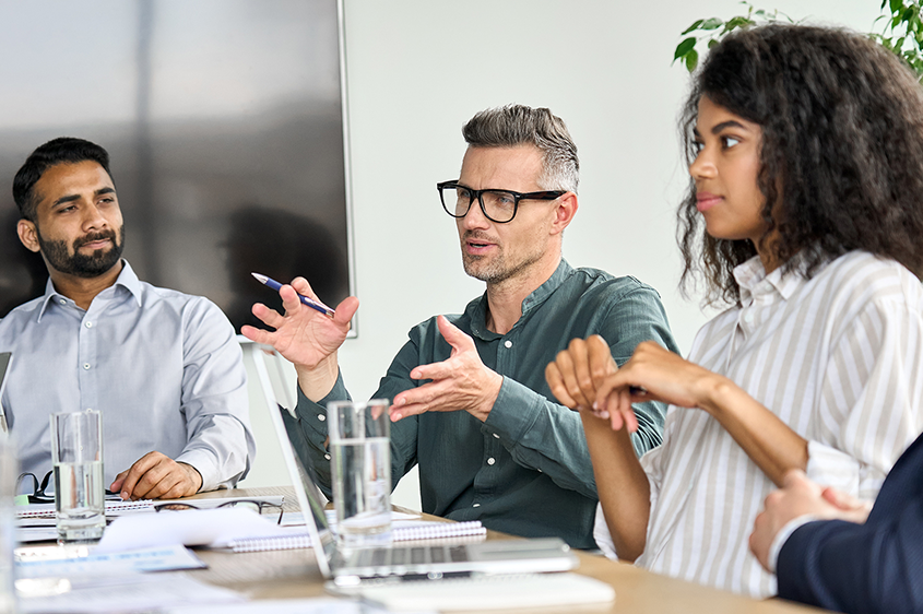 three colleagues in a conference room discussing