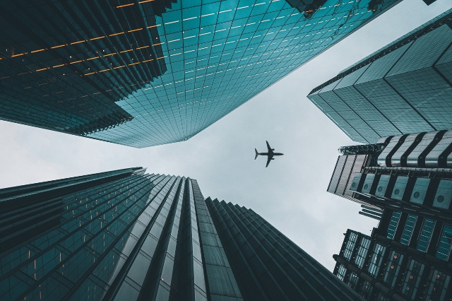 city sky view with sky scrappers and an airplane flying overhead