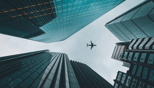 city sky view with sky scrappers and an airplane flying overhead