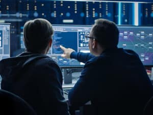two engineers sit in front of  a computer