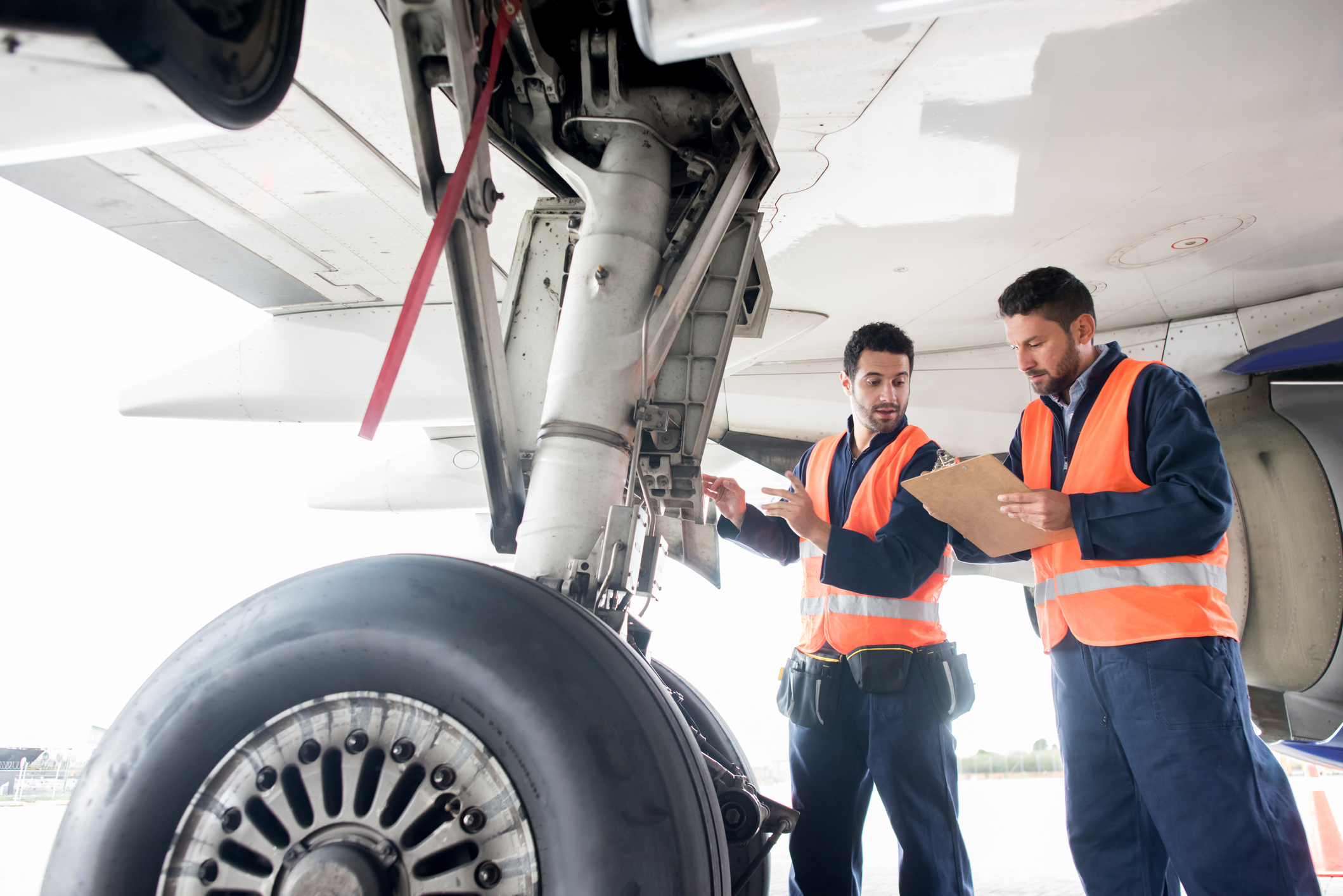 Airline workers examining plane wheel hydraulics
