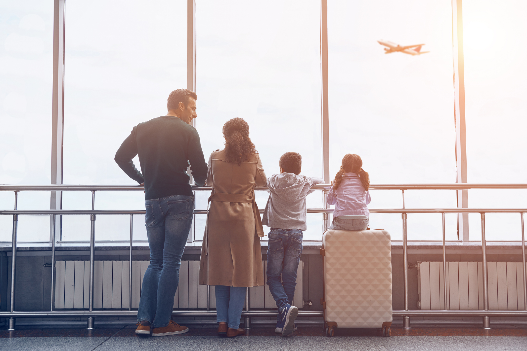 family with kids looking outside the window at a plane